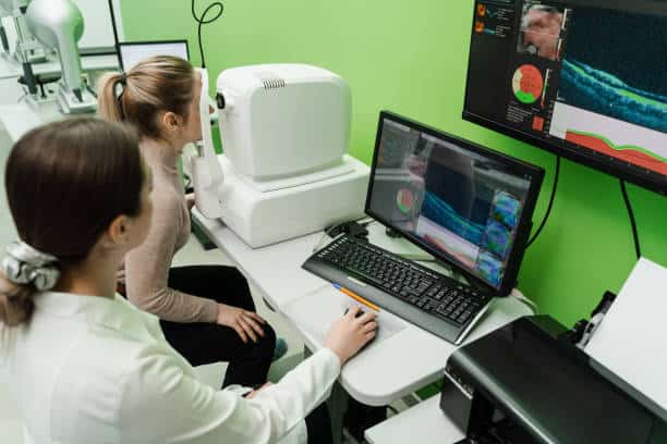 Examination of eyes of patient using optical coherence tomograph. Optical coherence tomography OCT scan to create pictures of the back of eye. Ophthalmologist is scanning cornea of woman patient