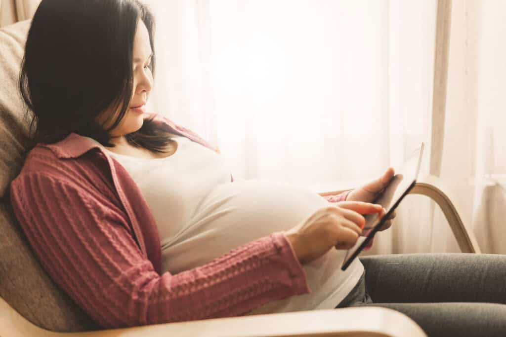 a pregnant woman scrolling through a tablet