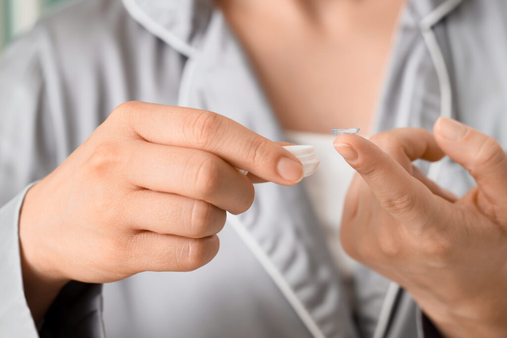 young woman taking contact lenses from container at home